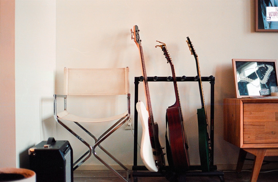 a-room-with-a-chair-and-a-rack-with-guitars-ddzgf5cve38